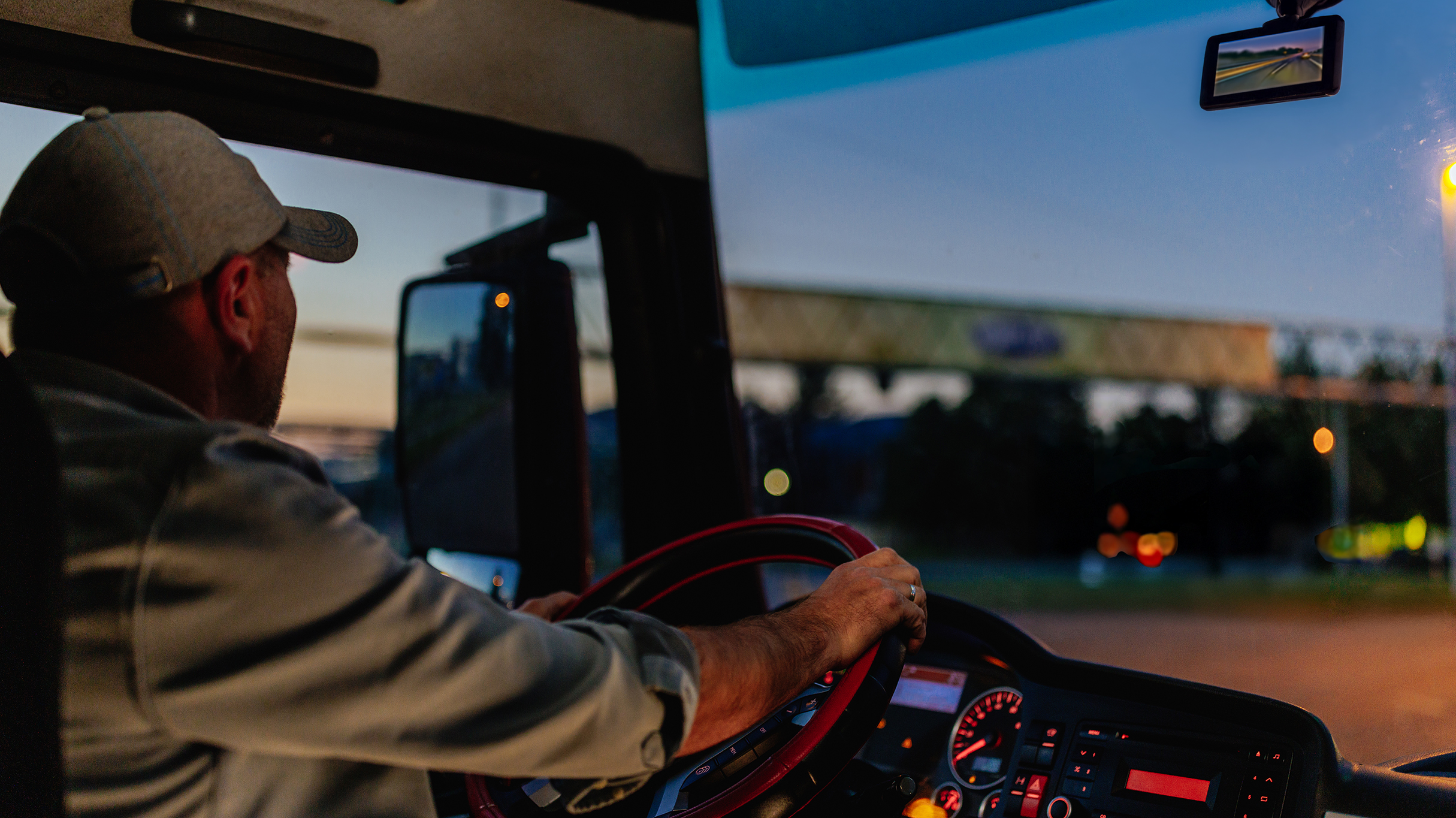 Inside of vehicle windshield at night showing dash camera and vehicle lights on the road in front.